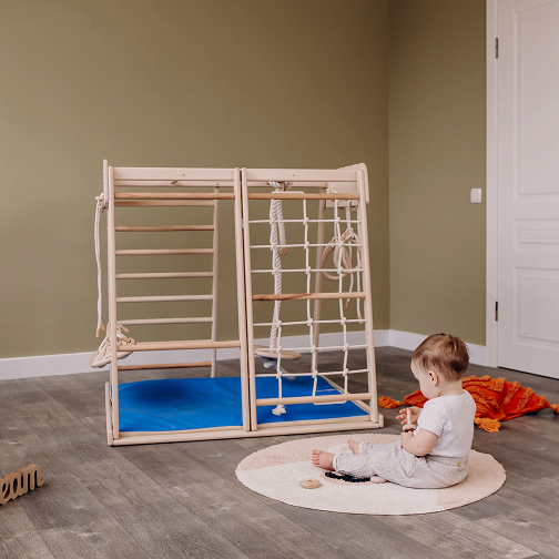 A picture of a baby sitting next to the jungle gym