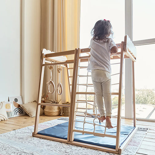 A picture of a kid climbing on the rope ladder of a jungle gym