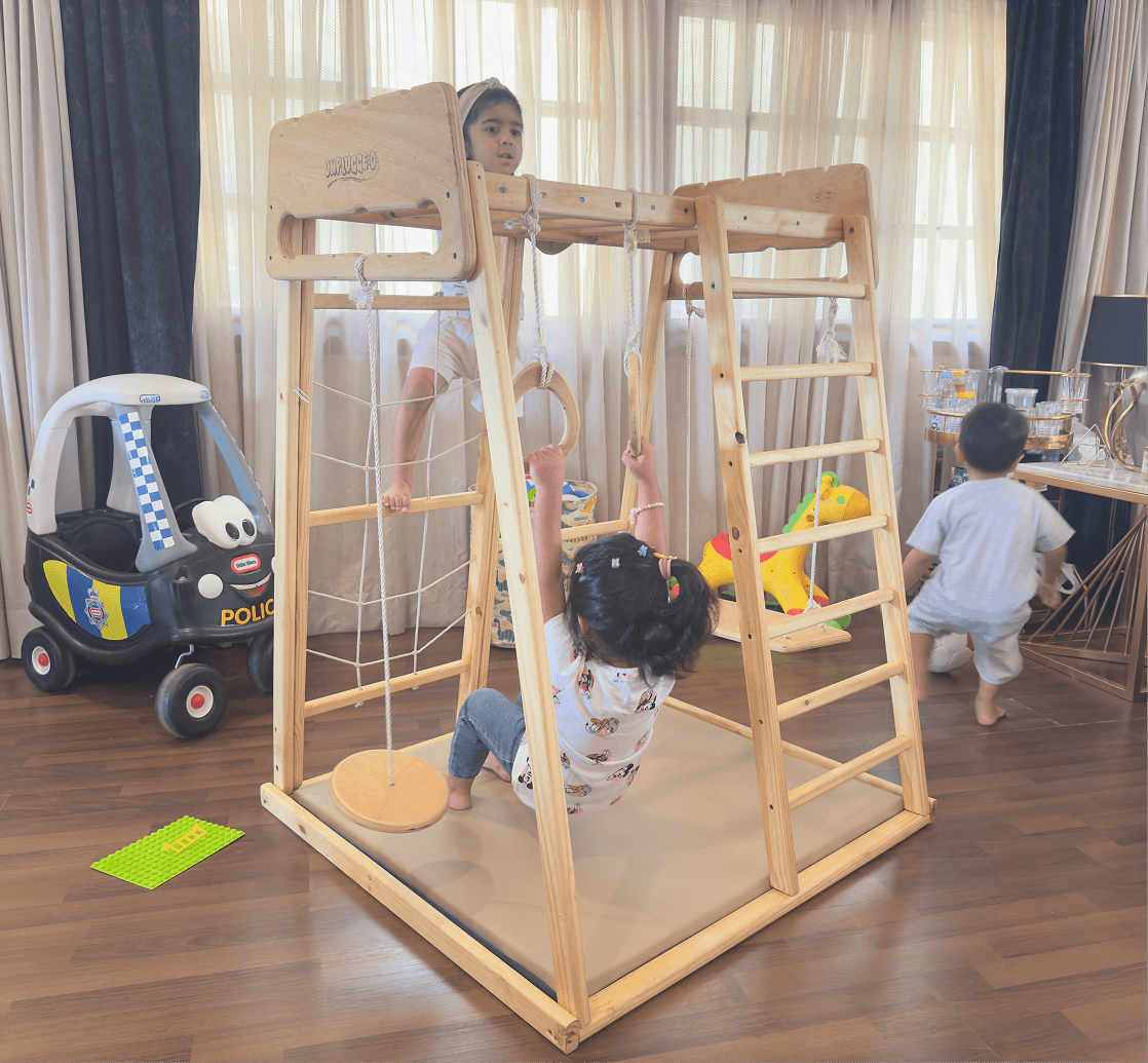 Children playing on a jungle gym in a room with toys and furniture.