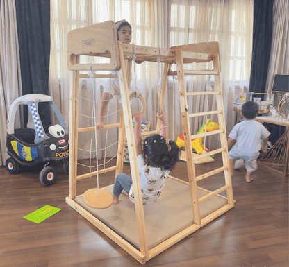 Children playing on a jungle gym in a room with toys and furniture.