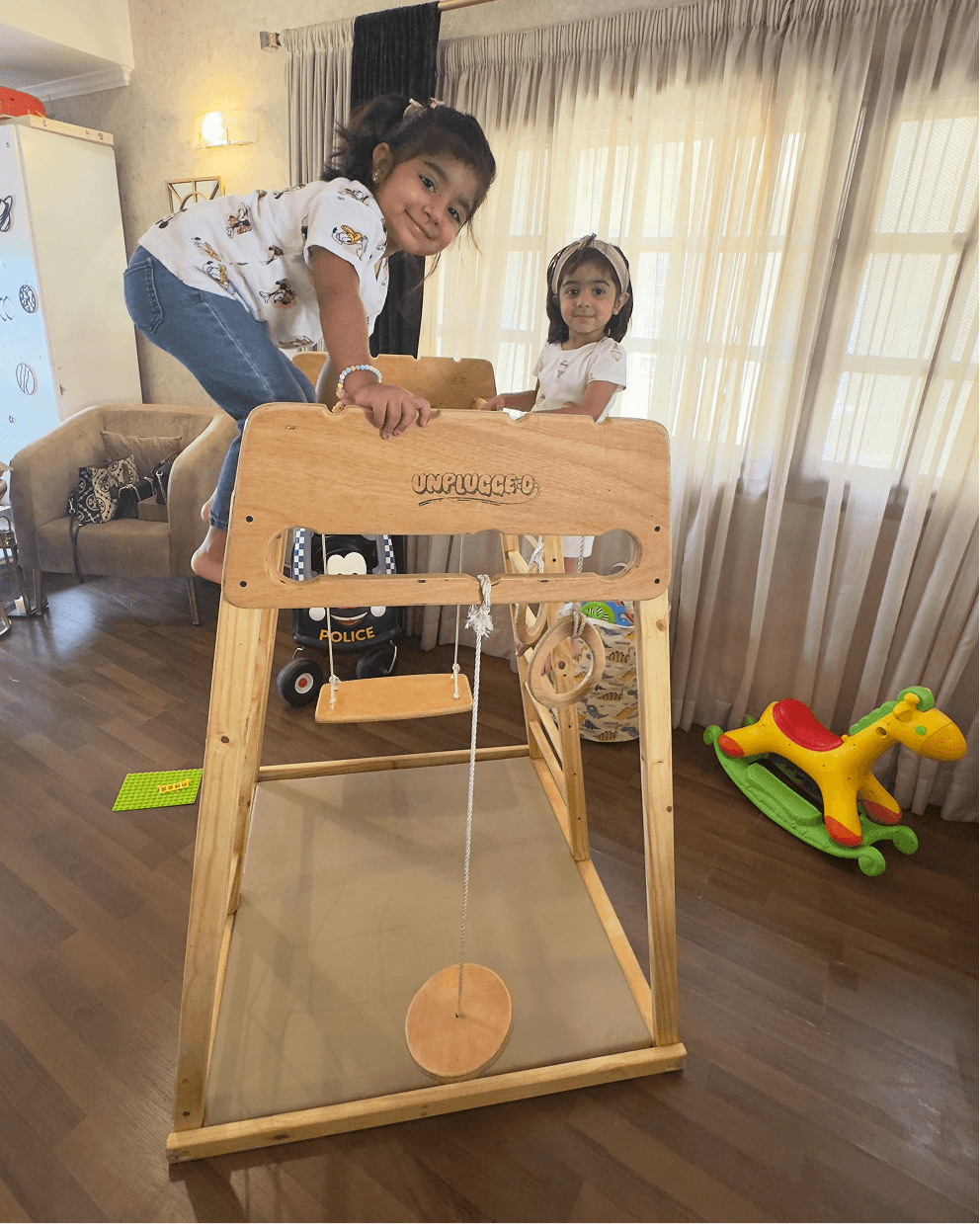 Children playing with a wooden jungle gym in a living room